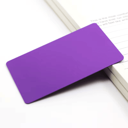 Studijska fotografija prikazuje ljubičastu praznu inkdžet PVC karticu za prilagođenu štampu postavljenu pored notesa za prezentaciju proizvoda.