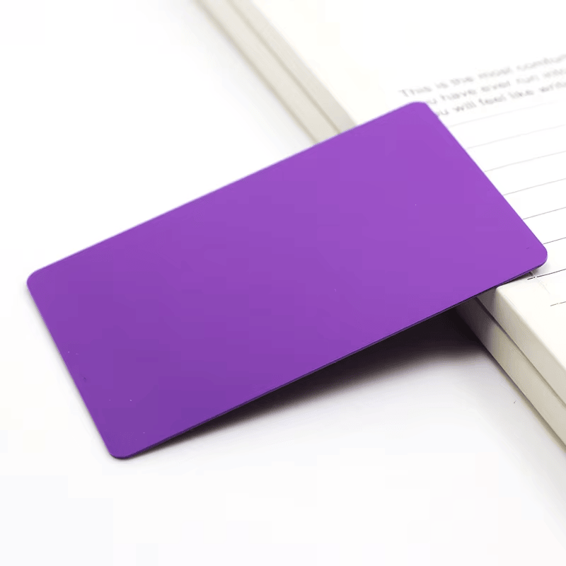 Prazna ljubičasta PVC kartica za inkdžet štampu po želji leži pored otvorene sveske kao primer svakodnevne upotrebe identifikacione kartice.