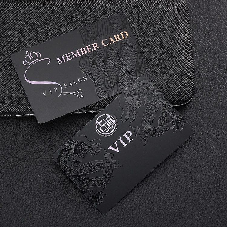 Dve mat crne VIP plastične kartice sa grafikom zmaja i dizajnom člana salona prikazane na koži radi prikaza detaljne štampe uzorka.