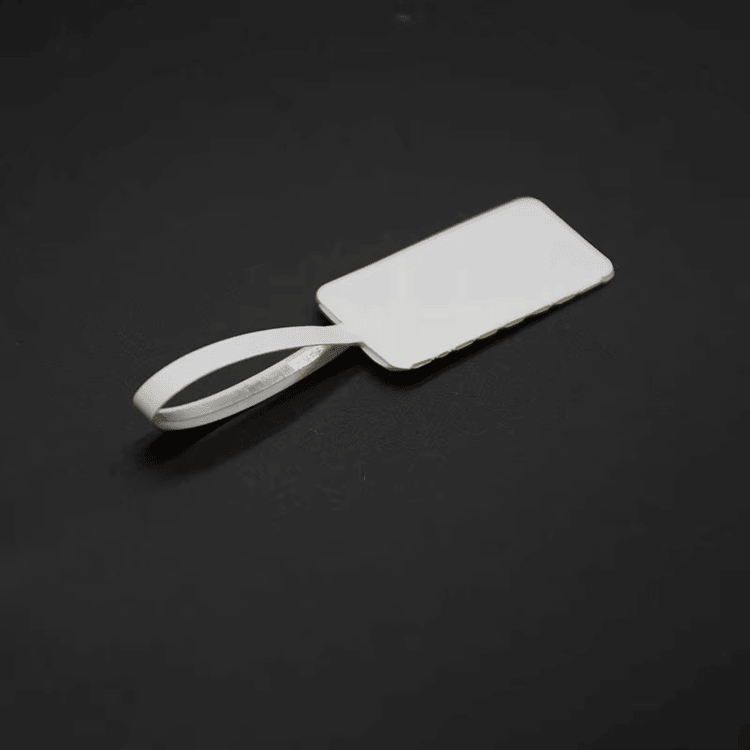 Prazna RFID etiketa za nakit prikazana je na tamnoj pozadini koja ističe glatku površinu za štampu i repić za petlju.