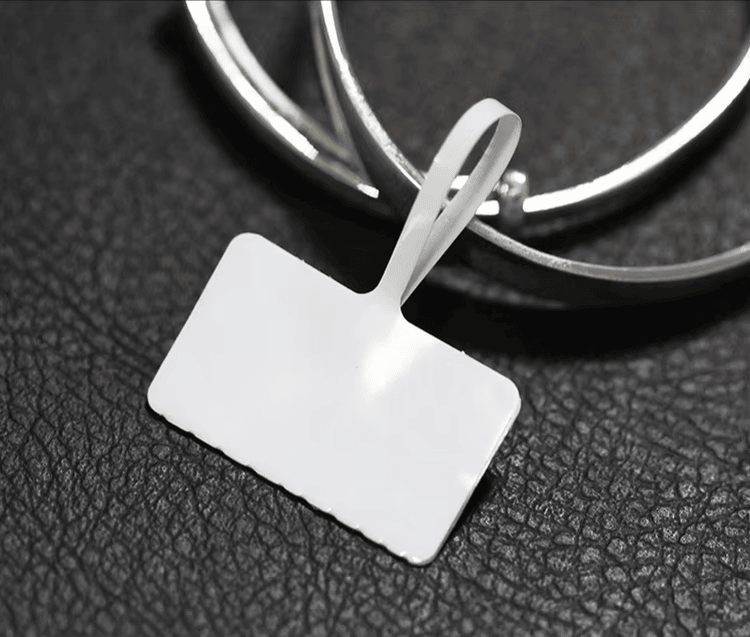 Prazna RFID etiketa za nakit nalazi se pored metalnih narukvica kako bi se ilustrovao oblik oznake i način pričvršćivanja u upotrebi.