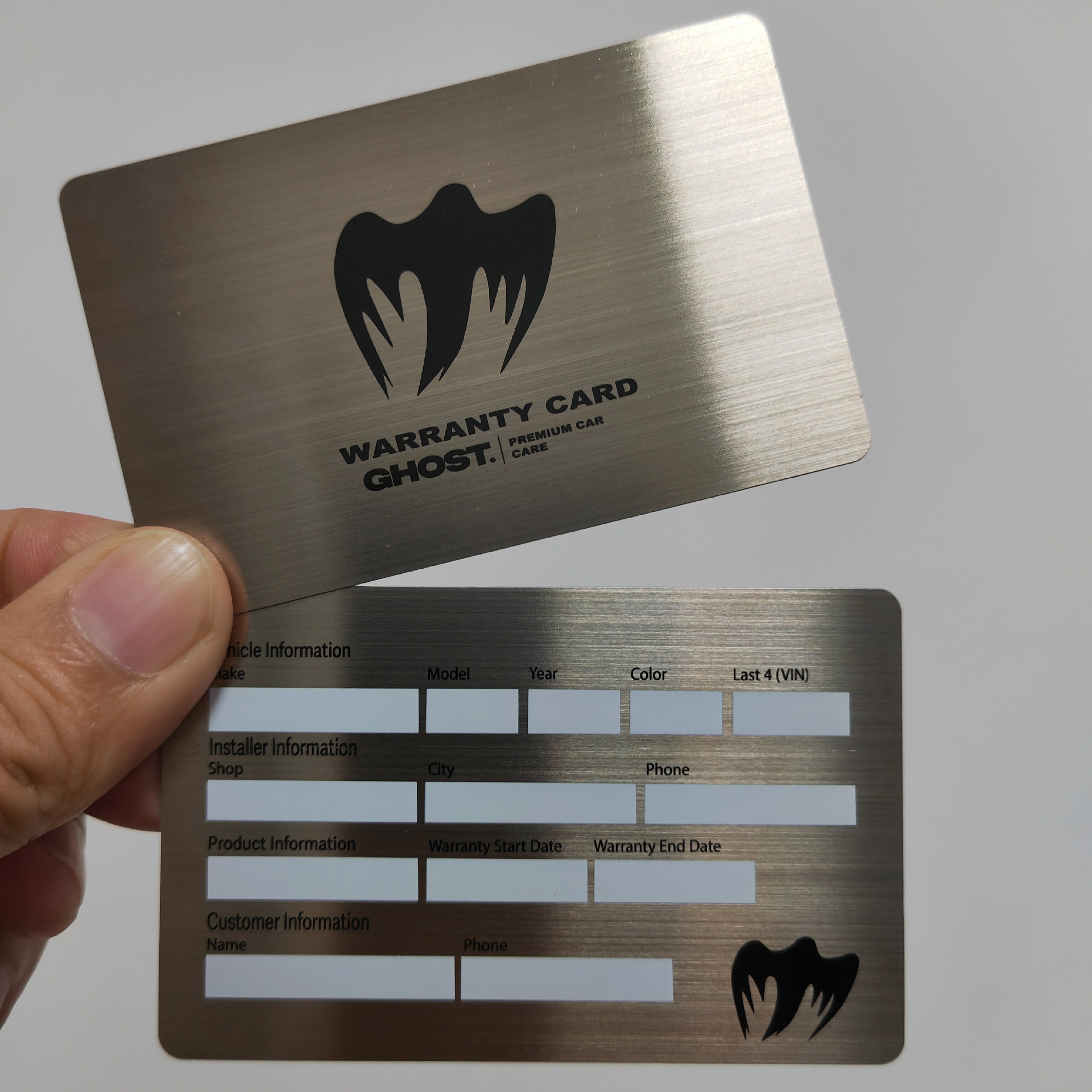 Detaljan snimak prikazuje garancijske kartice od nerđajućeg metala sa diskretnim logotipom i strukturiranim poljima za evidenciju servisa.