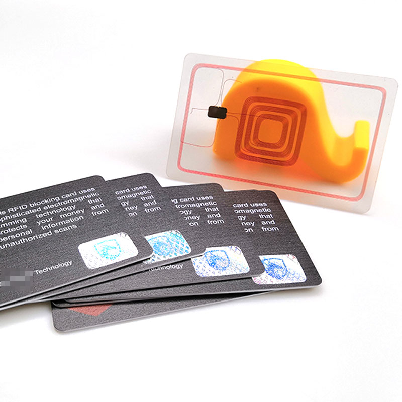Transparentna kartica otkriva RFID antenu i čip pored raspoređenih RFID blokirajućih kartica sa hologramskim nalepnicama na vrhu.