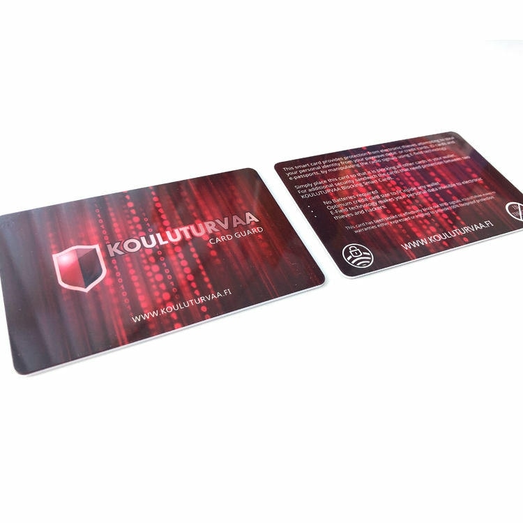Dve RFID zaštitne kartice Kouluturvaa Card Guard prikazuju logotip na prednjoj strani i tekst uputstva na zadnjoj sa crvenim uzorkom.