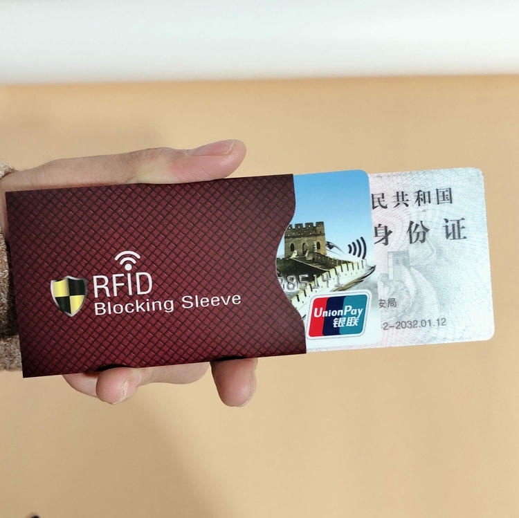 Ruka izvlači identifikacionu karticu iz crvene futrole za blokiranje RFID signala radi prikaza zaštite beskontaktnih kartica od krađe.