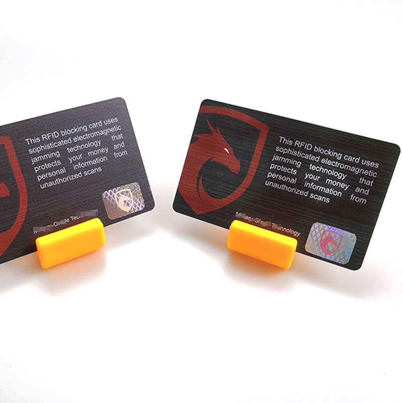Par RFID zaštitnih kartica prikazanih na žutim stalkama prikazuje štampani tekst o tehnologiji ometanja i hologramske etikete za sprečavanje krađe.