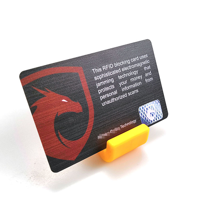 Pojedinačna RFID zaštitna kartica sa dizajnom crvenog štita prikazana je na žutom stalku sa štampanom izjavom o blokiranju skeniranja.