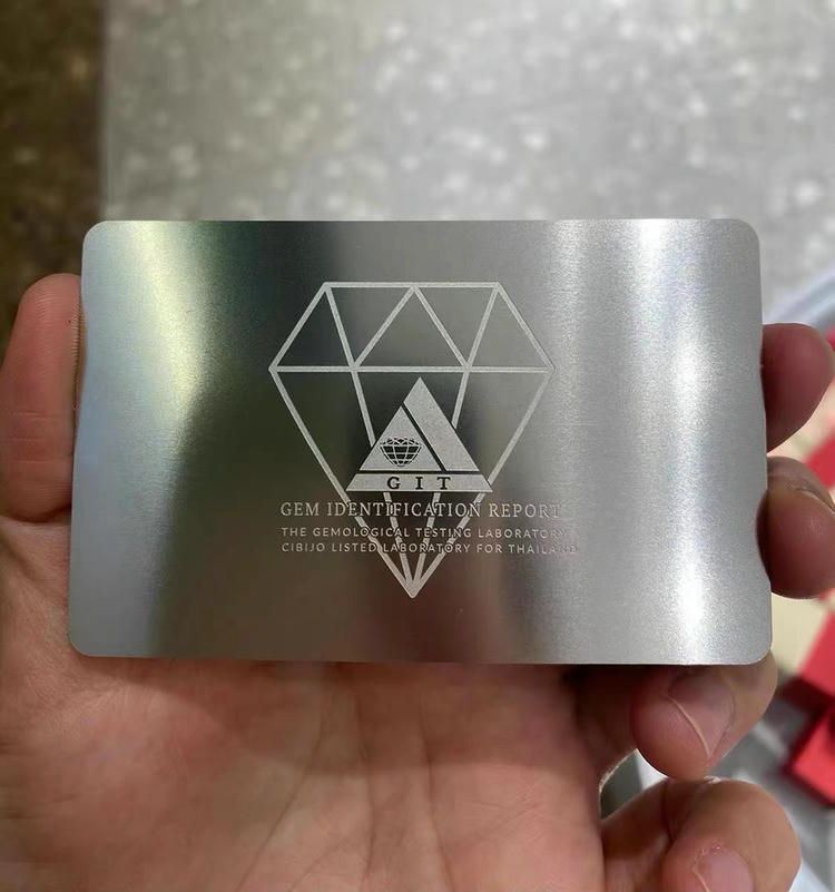 Luksuzna VIP metalna vizit karta od brušenog srebra sa grafikom u dijamantskom stilu, držana u ruci radi isticanja preciznog graviranja na metalu.