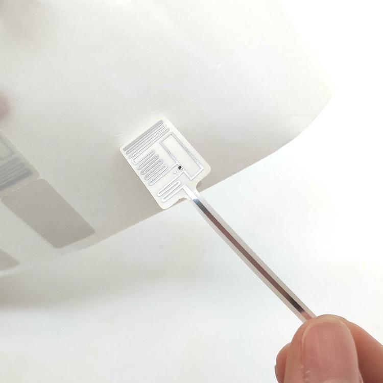 Krupni prikaz pokazuje jednu RFID etiketu za nakit odlepljenu sa zaštitne podloge kako bi se otkrili obrazac antene i struktura oznake.