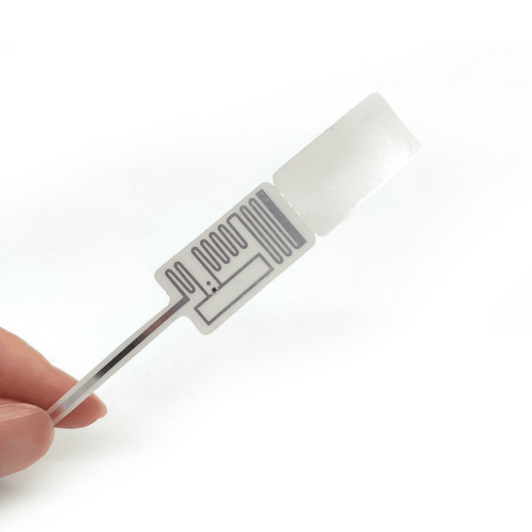 Pojedinačna RFID nalepnica za nakit prikazana je u ruci sa jasno vidljivom antenom za označavanje na nivou predmeta.