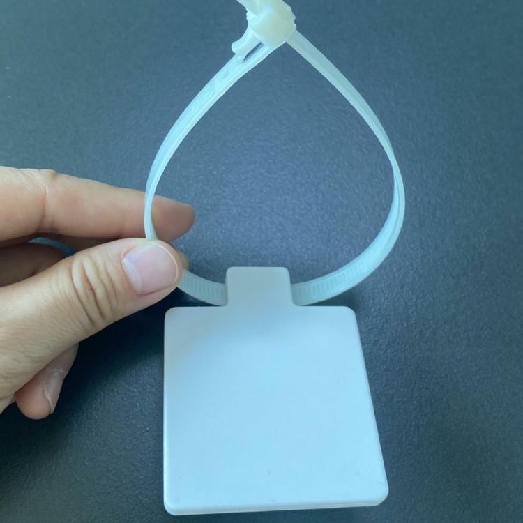 Ruka drži RFID tag u obliku kablovske vezice model Z5555-1 da prikaže savitljivu najlonsku traku u petlji i prazan kvadratni panel spreman za štampu.
