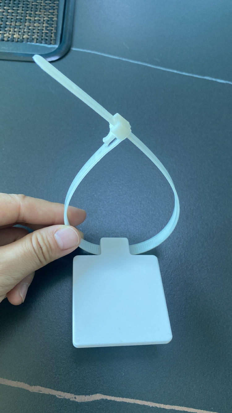 Detalj iz blizine prikazuje RFID tag u obliku kablovske vezice model Z5555-1 sa uključenom glavom za zaključavanje i repom trake koji se pruža iznad kvadratnog panela.