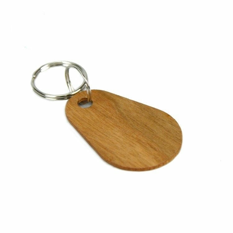 Neštampani ovalni drveni RFID privezak sa razdvojenom metalnom alkom prikazuje glatku teksturu drveta i zaobljene ivice za vodootporan pristup po meri.