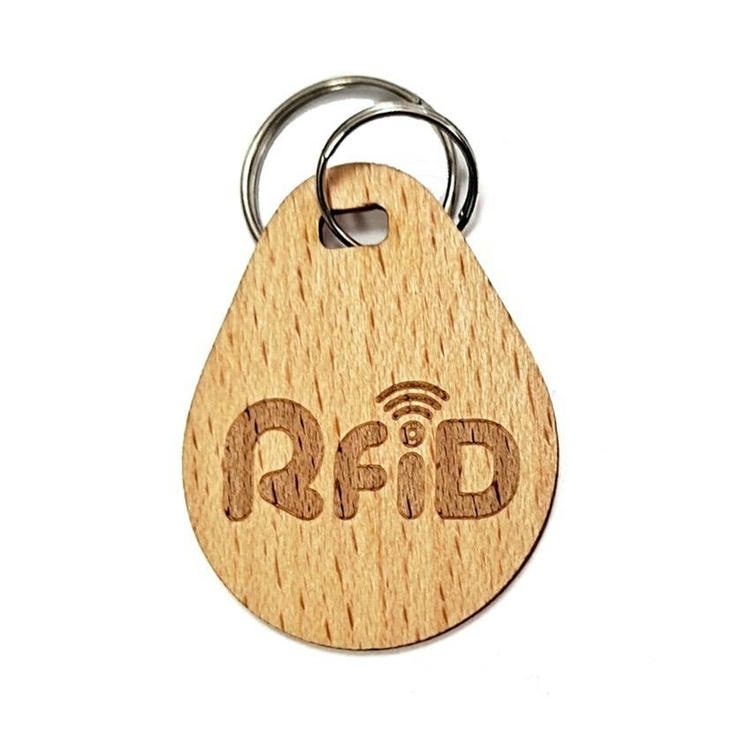Krupni plan prikazuje drveni RFID privezak u obliku kapi sa izrezanim slovima RFID i razdvojenom alkom za vodootpornu identifikaciju pristupa po meri.