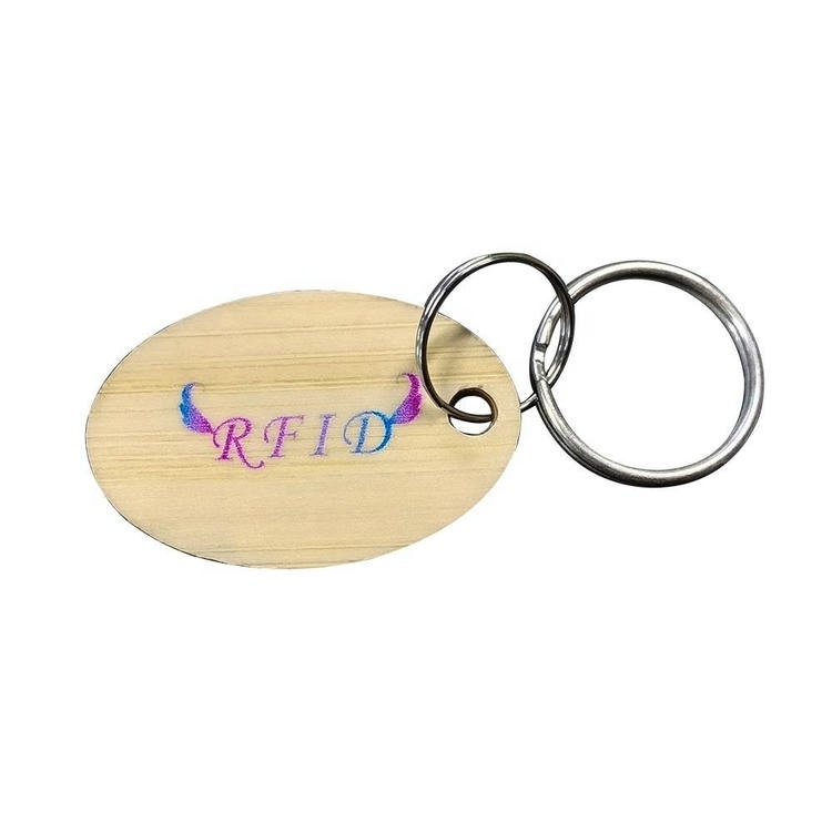 Ovalni drveni RFID privezak na alci ima šareni odštampani tekst RFID za brendirani pristup hotelskim sobama i ulaz posetilaca.