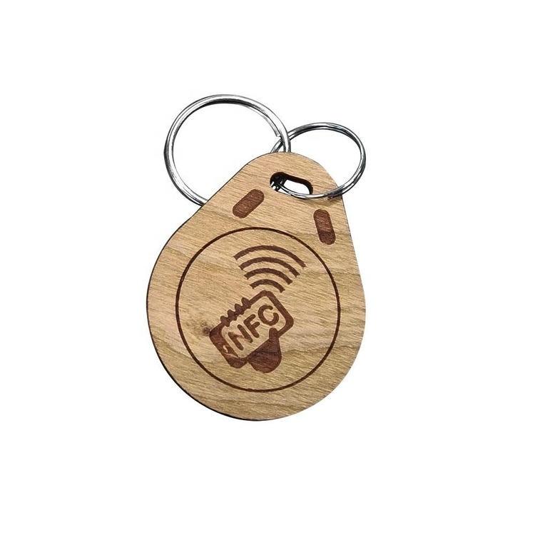 Drveni RFID privezak u obliku kapi sa alkom ima NFC simbol ruke graviran unutar kruga na prirodnoj teksturi drveta.