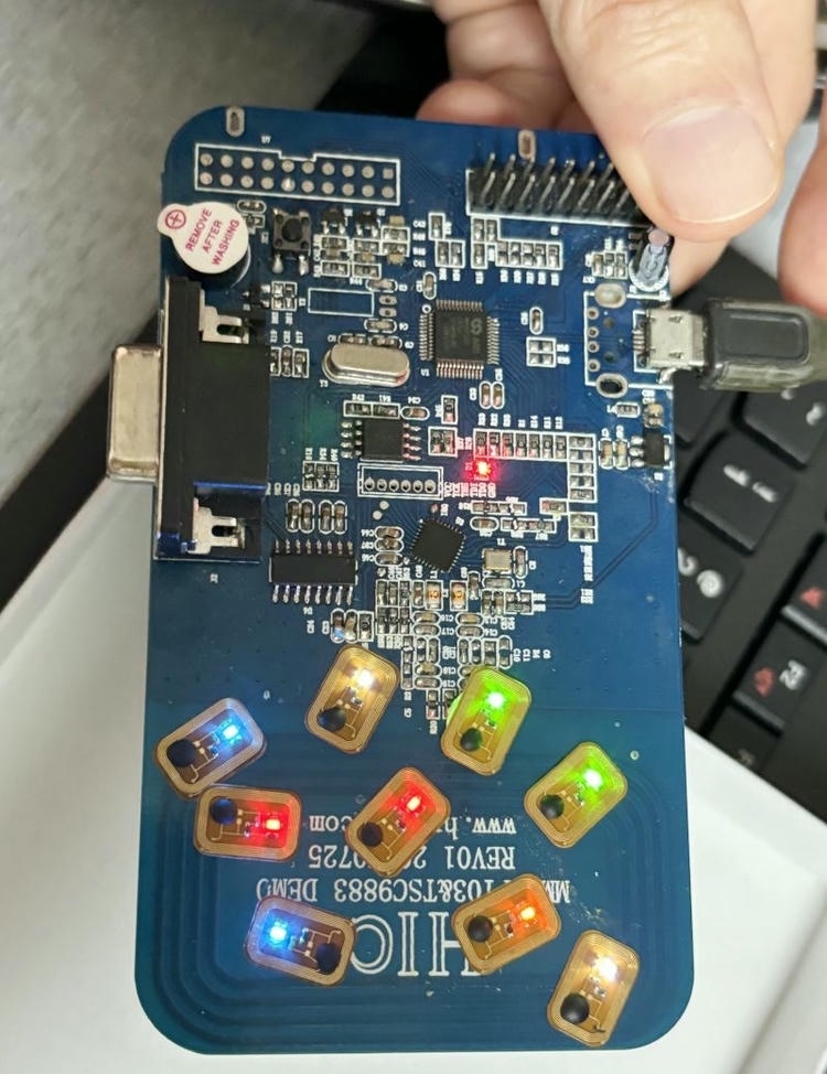 Nekoliko FLED1006-1 NFC LED oznaka svetli različitim bojama na plavoj testnoj ploči tokom provere elektronskih funkcija.