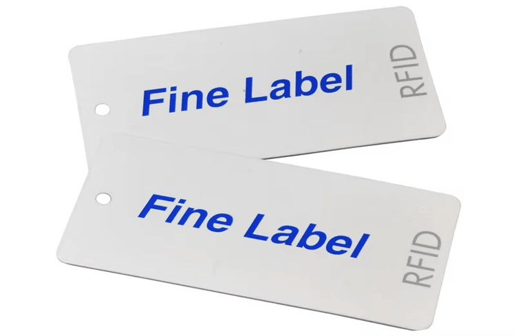 Dve bele RFID tekstilne etikete za odeću štampane sa brendom Fine Label prikazane su da pokažu čist prilagođeni stil oznaka za odeću.