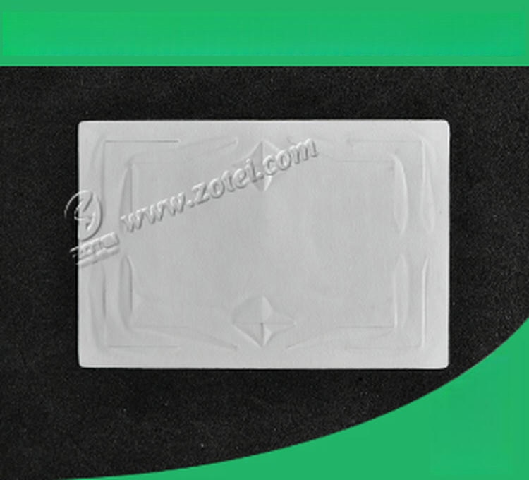 Jedna prazna UHF RFID oznaka za vetrobran leži ravno na crnoj pozadini sa zelenim uglovima koji ističu glatku površinu i reljefnu antenu.