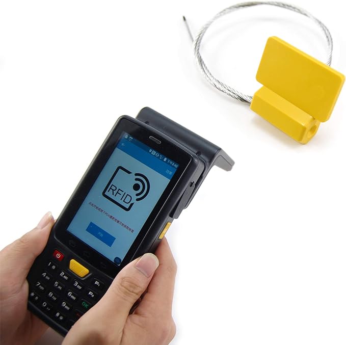 Ručni RFID čitač je prikazan pored žute SS3826-1 RFID sigurnosne plombe radi demonstracije beskontaktne identifikacije.