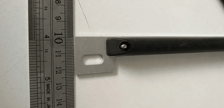 Krupni plan prikazuje montažni jezičak i tačku za zavrtanj RFID taga za metalne površine pored lenjira radi prikaza veličine hardvera za instalaciju.