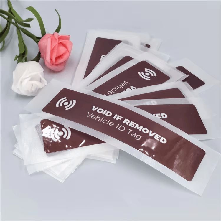 Veliki skup RFID etiketa za vetrobran koje pokazuju pokušaj uklanjanja nalazi se u providnim omotima s oznakama vozila VOID IF REMOVED spremnim za distribuciju.