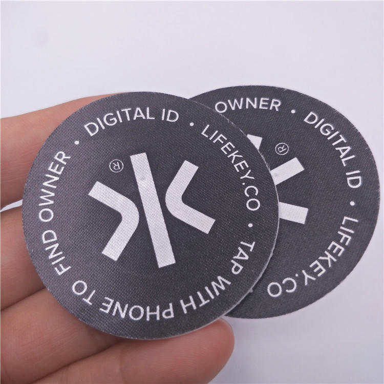 Prilagođeni tkani NFC bedž sa logom koji kombinuje tradicionalno brendiranje sa savremenim mogućnostima digitalne interakcije.