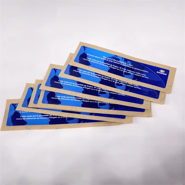 Gomila RFID nalepnica za vetrobran s plavom štampom u kraft omotima fotografisana je na beloj pozadini za identifikaciju vozila pri parkiranju voznog parka.