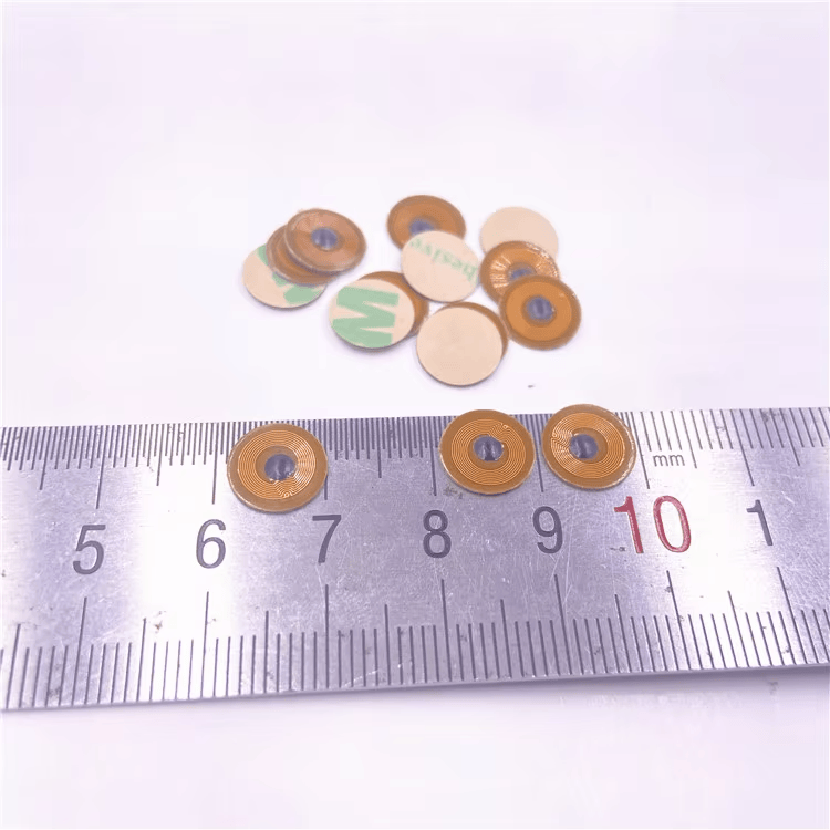 FPC10-1 10mm mikro RFID tag prikazan sa lenjirom i setom tagova radi prikaza kompaktne veličine za metalne predmete zaštićene od neovlašćenog otvaranja.