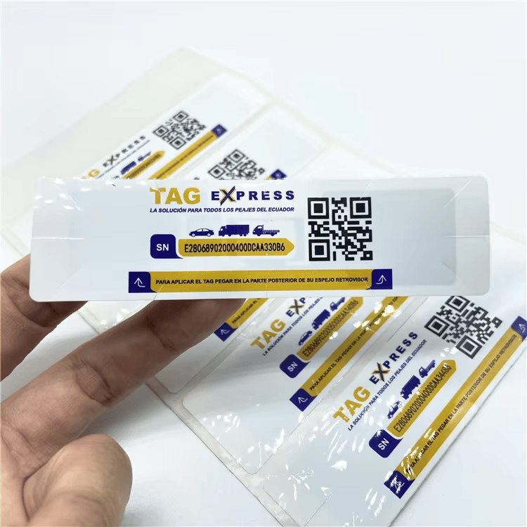 Prst pokazuje na jednu UHF RFID nalepnicu za pristup kroz vetrobransko staklo sa natpisom TAG EXPRESS, QR kodom i površinom za serijski broj.