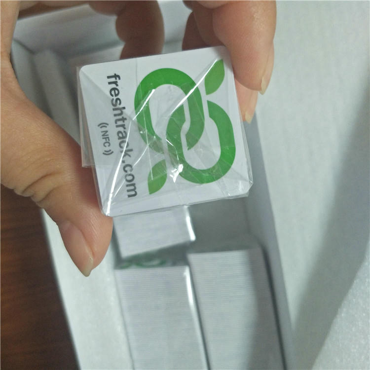 Bele kvadratne PVC NFC pametne oznake prilagođene plavim korporativnim logotipom za identifikaciju brenda i kontrolu pristupa.