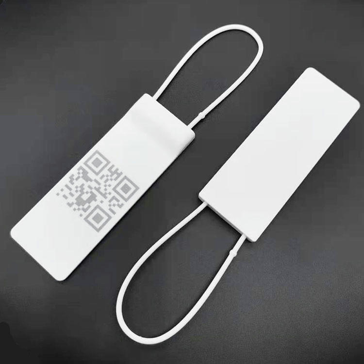 Set od dve bele RFID platnene viseće oznake prikazan je na tamnoj pozadini, pri čemu je jedna oznaka štampana QR kodom za praćenje predmeta.