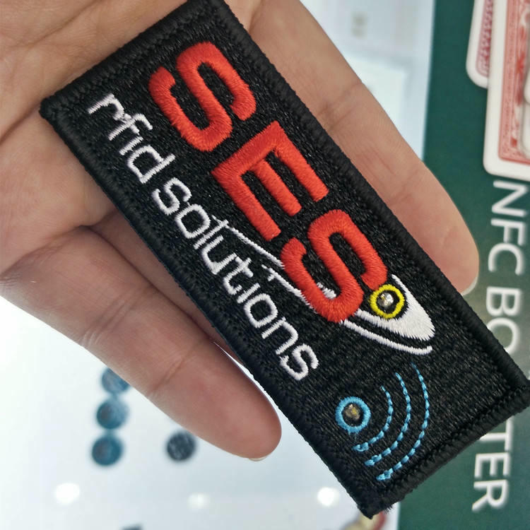Prednja strana kvalitetnog tkanog NFC amblema za odeću sa detaljnim vezom i tehnologijom pametnog čipa.