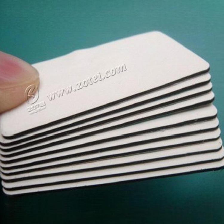 Izbliza prikaz složenih PVC na metal RFID tagovima sa zaobljenim uglovima i slojevitom anti metal podlogom na tirkiznoj površini.