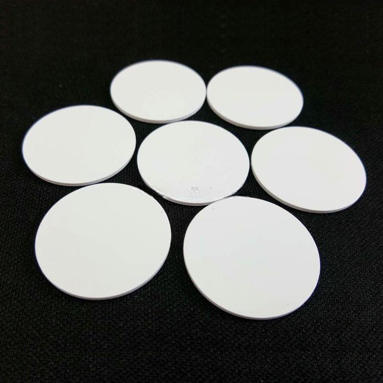 Nekoliko PVC RFID oznaka u obliku novčića raspoređeno je radi prikaza debljine i završne obrade ivica za vodootpornu upotrebu na otvorenom i u radionici.
